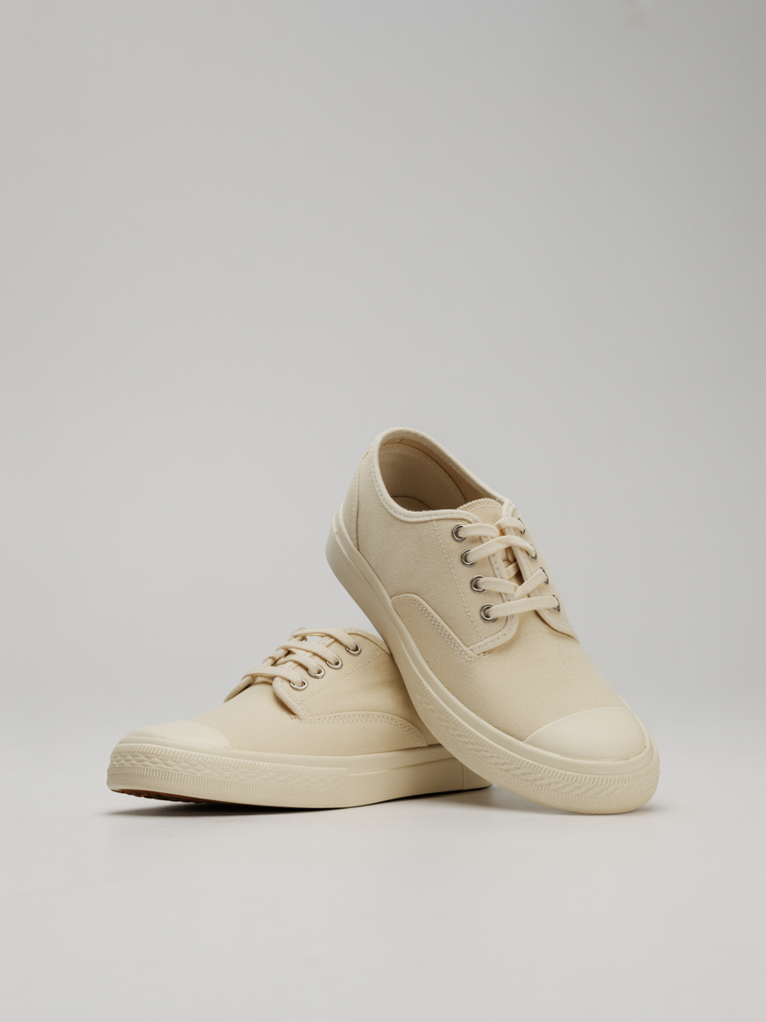 A pair of premium canvas shoes displayed on a minimalist background. The canvas shoes feature natural canvas uppers with a durable construction, comfortable rubber sole, and versatile design. Handcrafted in Portugal, these canvas shoes exemplify the perfect balance of comfort, sustainability and casual style.