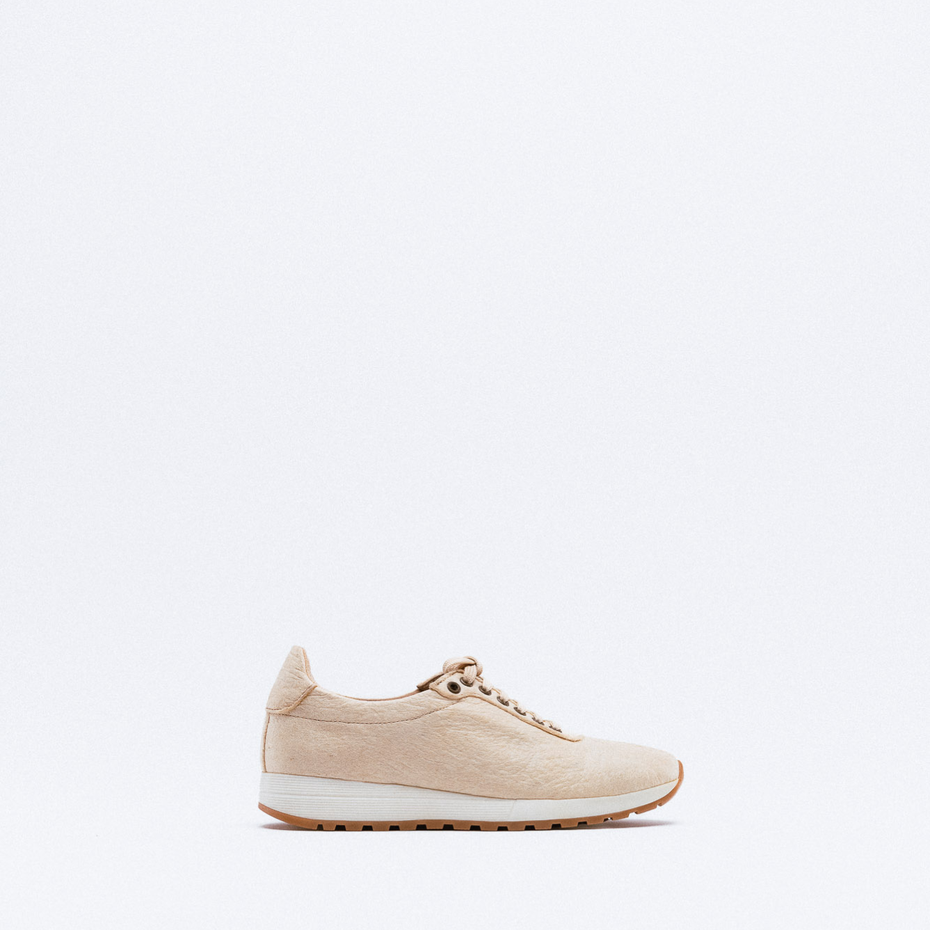 A beige textured leather sneaker with matching laces, white midsole and gum rubber outsole.