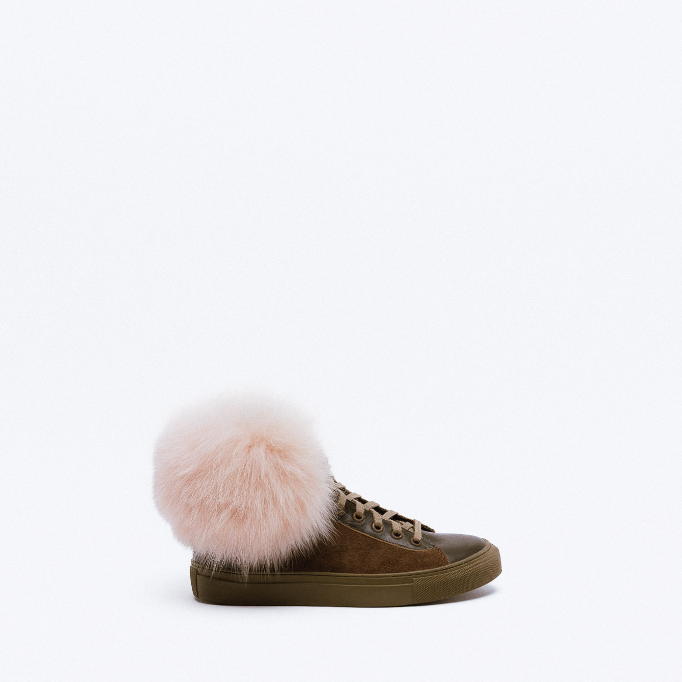 A brown leather sneaker with olive green sole and large pink fur pom-pom detail.