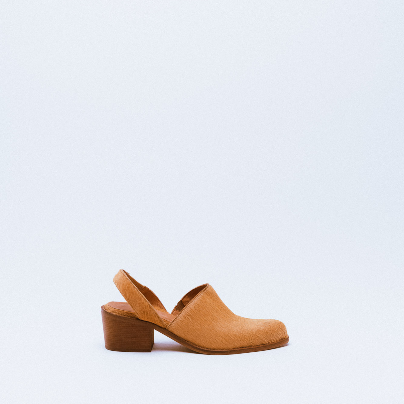A tan textured leather clog with slingback strap and wooden block heel.