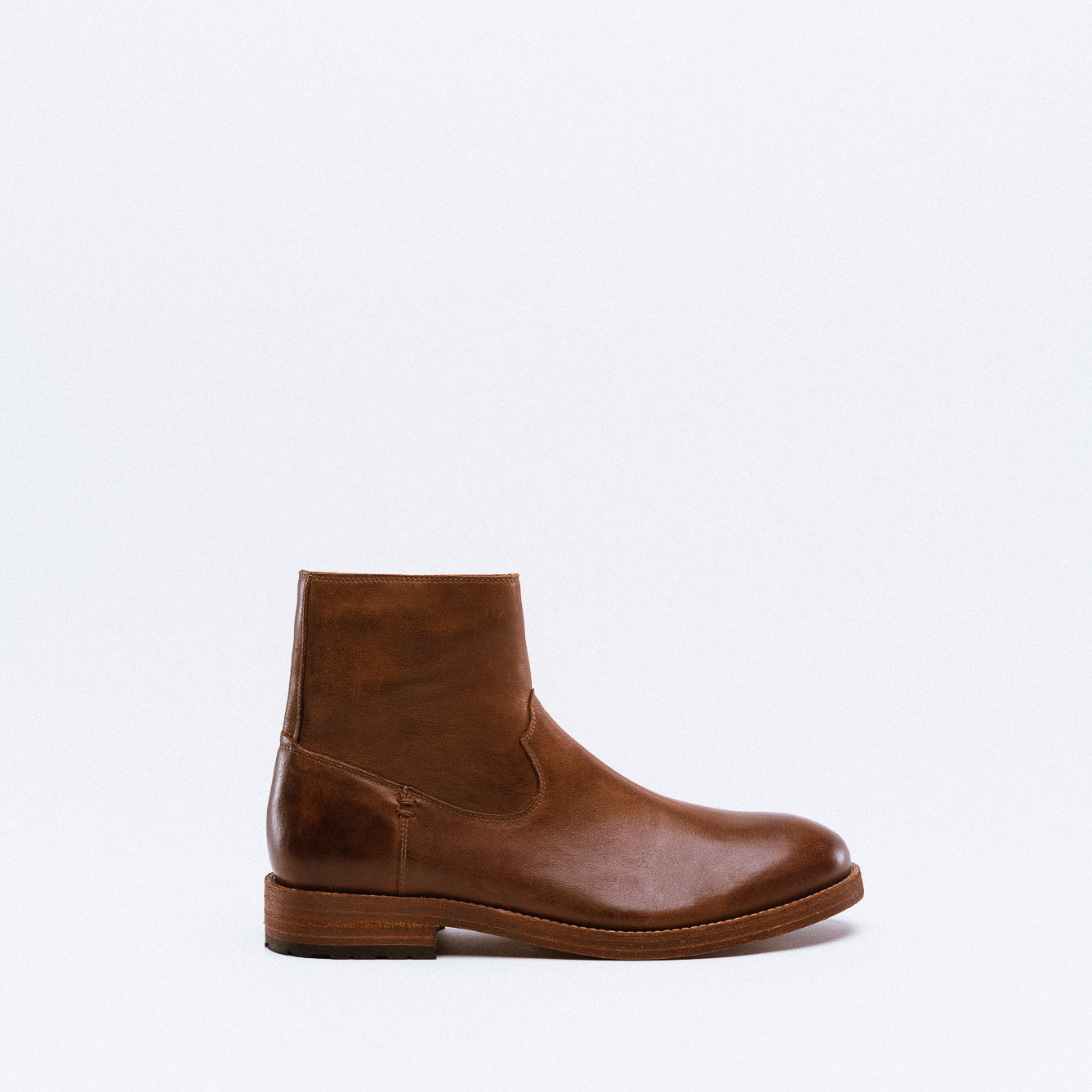 A brown leather ankle boot with mixed leather textures and a wooden stacked heel.