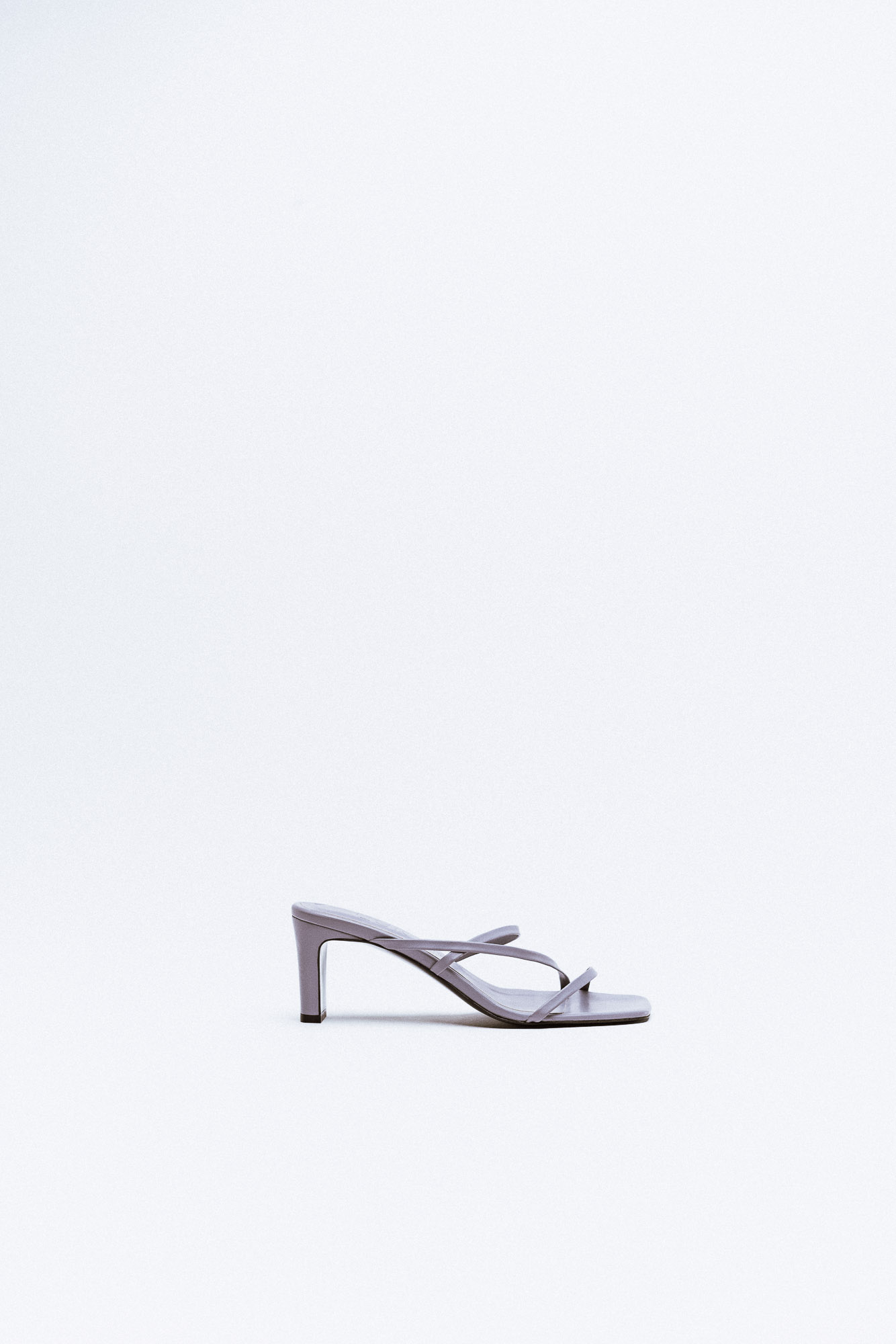 A leather mule with thin straps in lavender-gray, featuring a sleek heel and smooth finish.