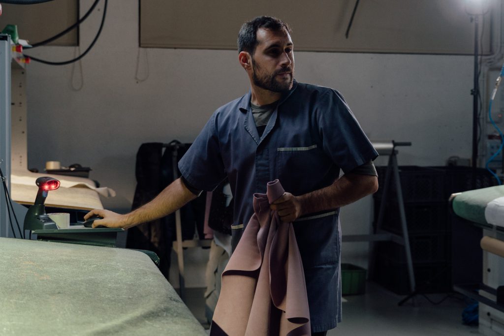 Factory worker with leather material at the factory, he is has passion in his eyes.