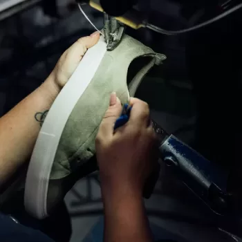 Person making a shoe sample in a machine at the factory.