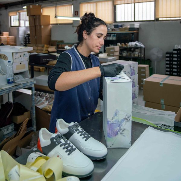 Factory worker packing and labeling sneakers.